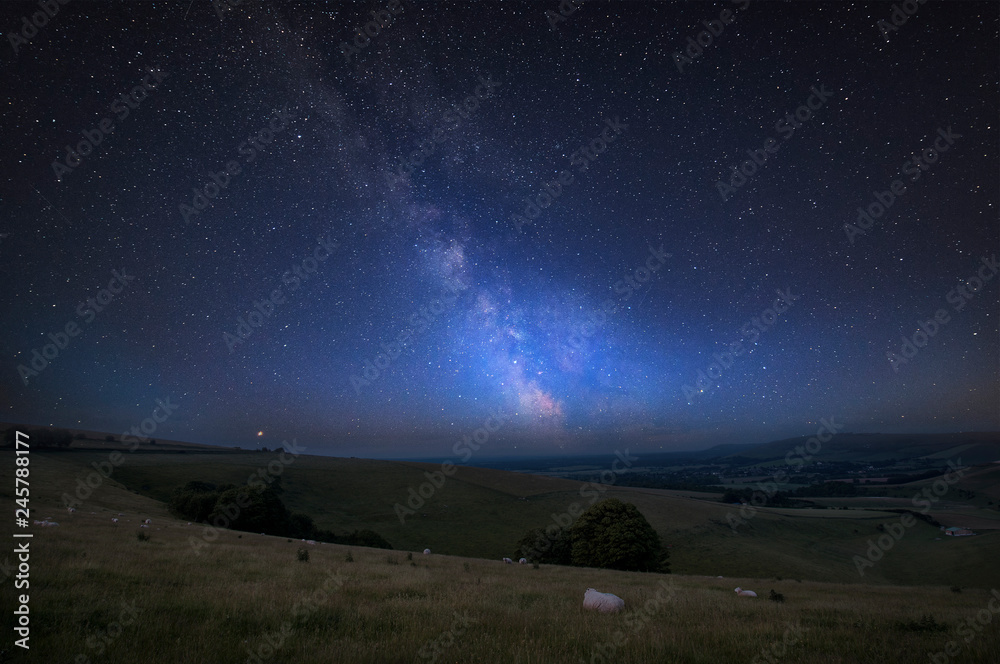 Vibrant Milky Way composite image over landscape of Steyning Bowl on South Downs