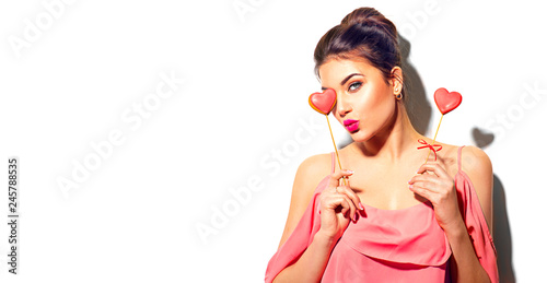Valentines Day. Beauty joyful young fashion model girl with Valentine heart shaped cookies in her hands isolated on white