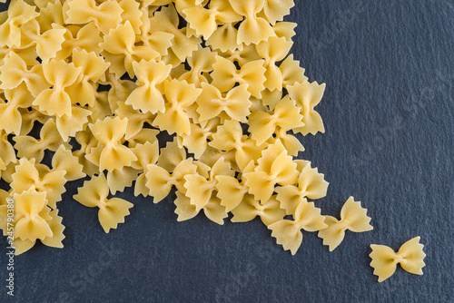 Wholemeal farfalle pasta on a dark background . Italian cuisine concept with copy space for your text.