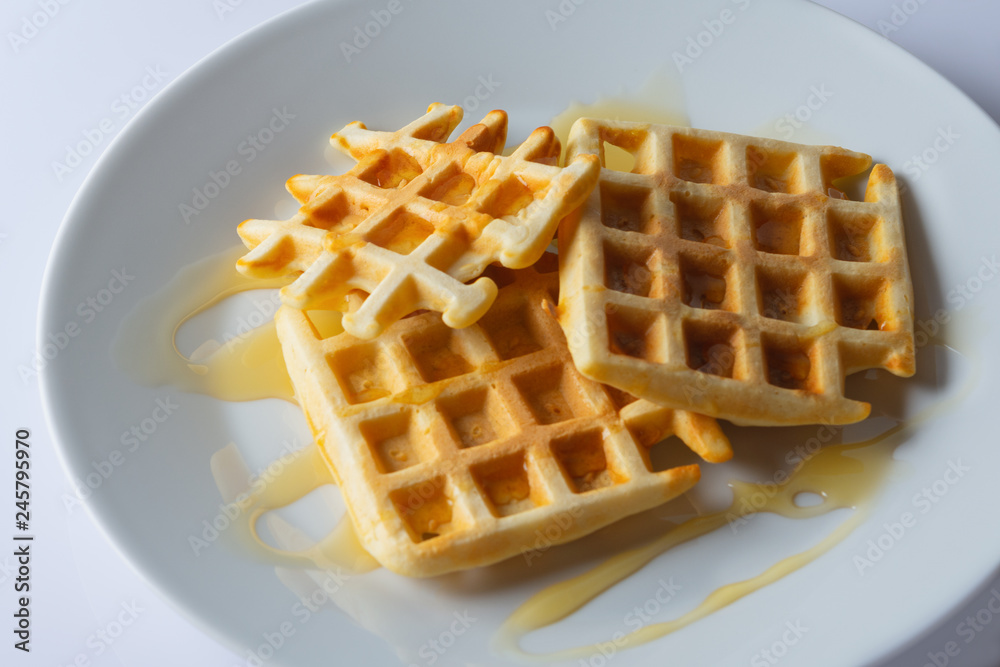 Viennese, Belgian waffles with honey on a white plate. Selective focus. Viennese, Belgian waffles with honey on a white plate. Selective focus.