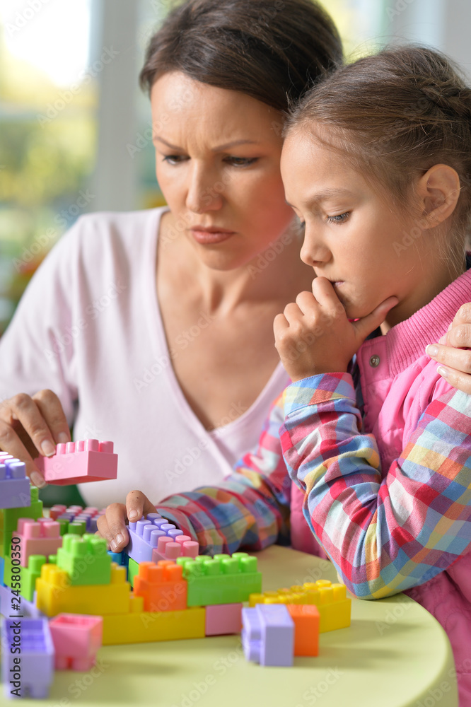 girl and her mother playing with colorful plastic blocks