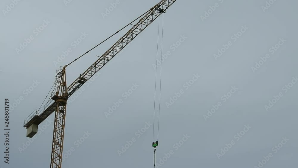 Grúa de construcción en movimiento giratorio, elevando gancho con cadenas