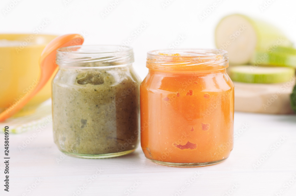 Broccoli and pumpkin vegetable puree in jars on white wooden background near ingredients Broccoli and pumpkin vegetable puree in jars on white wooden background near ingredients