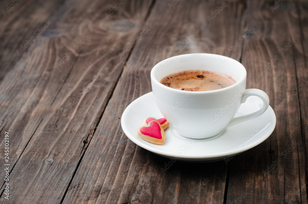Cup of coffee with heart cookies on rustic wooden background