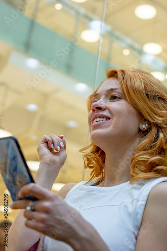 Young Women using the phone in Modern Mall. Shopping Concept. Happy Women.