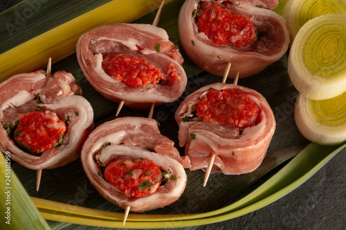 raw meat rolls on skewers, on green leaves, close-up