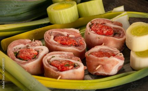 raw meat rolls on skewers, on green leaves, close-up