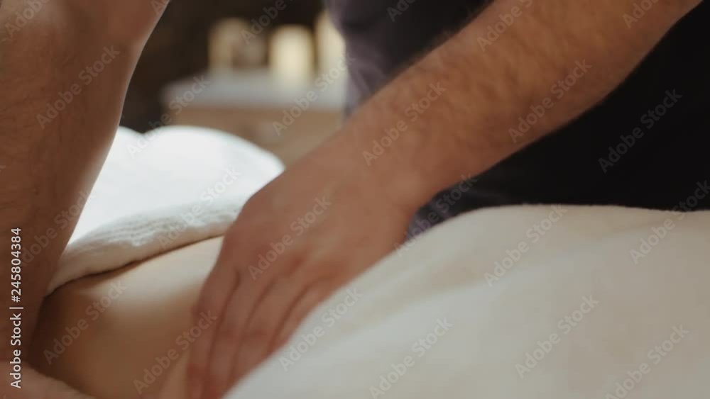 Male masseur hands burn fat by anti-cellulite massage. Woman receiving stomach massage at spa salon, relaxing lying on massage table during rejuvenation procedure Male masseur hands burn fat by anti-cellulite massage. Woman receiving stomach massage at spa salon, relaxing lying on massage table during rejuvenation procedure