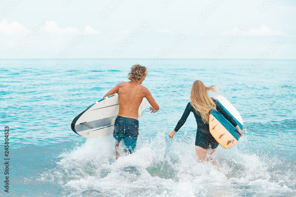 Φωτογραφία Surfers at the beach- Smiling couple of surfers swiming and having fun in summer