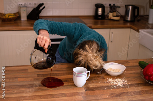 Müde Frau mit Kopf auf Tisch verschüttet ihren Kaffee
