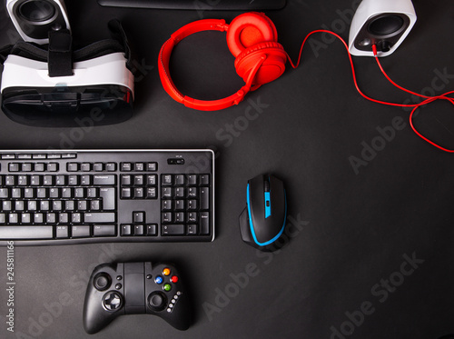 Top view a gaming gear, mouse, keyboard, joystick, headset, VR Headset on black table background.