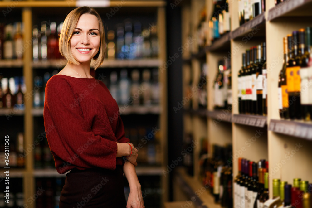 Photo of happy blonde woman in store with wine Photo of happy blonde woman in store with wine