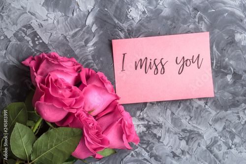 Romantic concept. Red roses and lettering I miss you on a gray concrete background