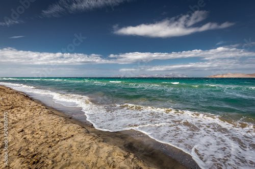 Sunny day on sandy Alikes beach near Tigaki with dramatic cloudy sky. Island of Kalymnos in background. Island of Kos, Greece
