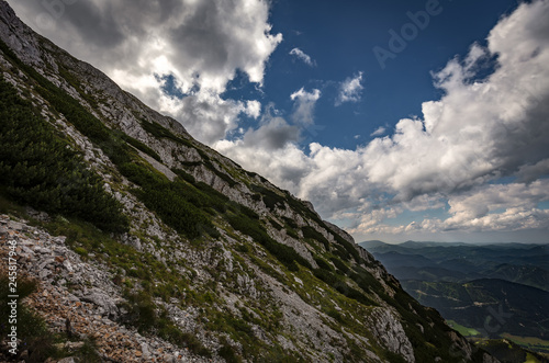 Scenic view on rocky route Nandsteig from Puchberg to Kaiserstein on Rax plateau, Schneeberg masif with dramatic cloudy sky and pine trees, Raxalpe, Lower Austria photo