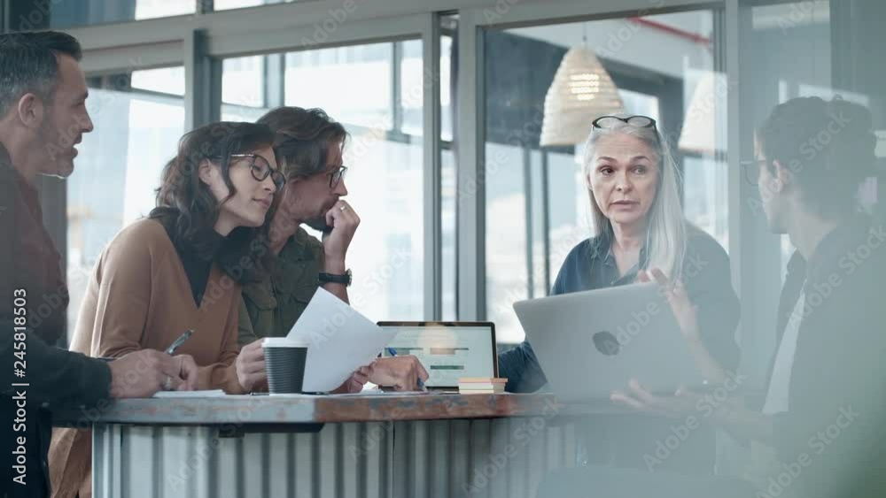 Professionals sitting around a table and discussing work. Business team brainstorming new business ideas during meeting at office.