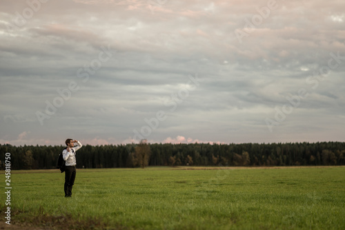 Young businessman standing in green meadow looking in to a distance