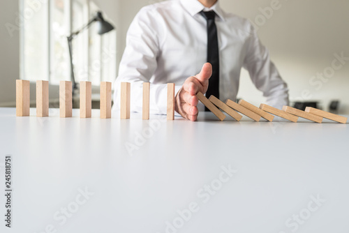 Businessman intervening to stop falling dominos
