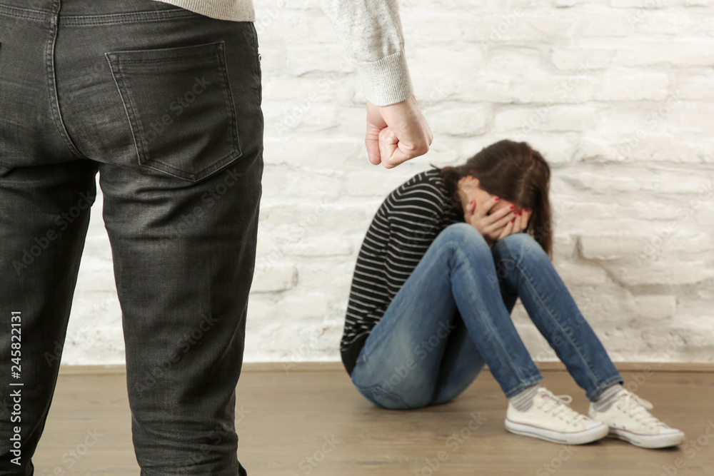 Violent husband abusing his terrified wife. Domestic violence concept. Focus on the clenched fist. Violent husband abusing his terrified wife. Domestic violence concept. Focus on the clenched fist.