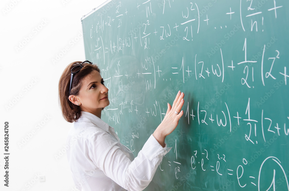 Female math teacher in front of the chalkboard Female math teacher in front of the chalkboard