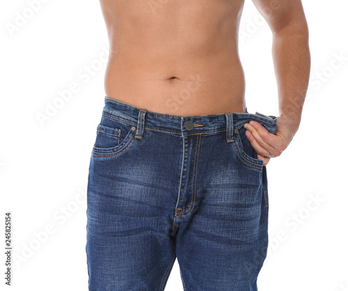 Fit man in oversized jeans on white background, closeup. Weight loss