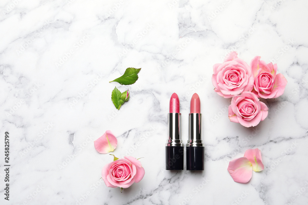 Fototapeta premium Flat lay composition with lipsticks, roses and space for text on marble background