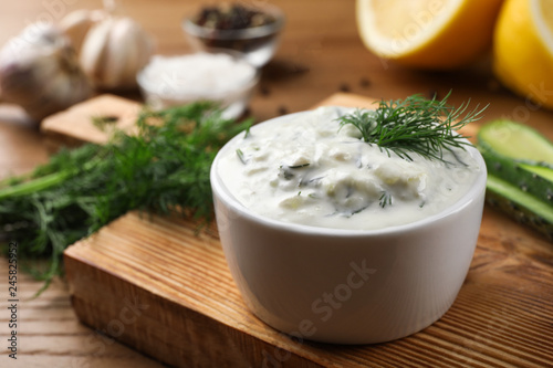 Cucumber sauce with ingredients on wooden background, space for text. Traditional Tzatziki