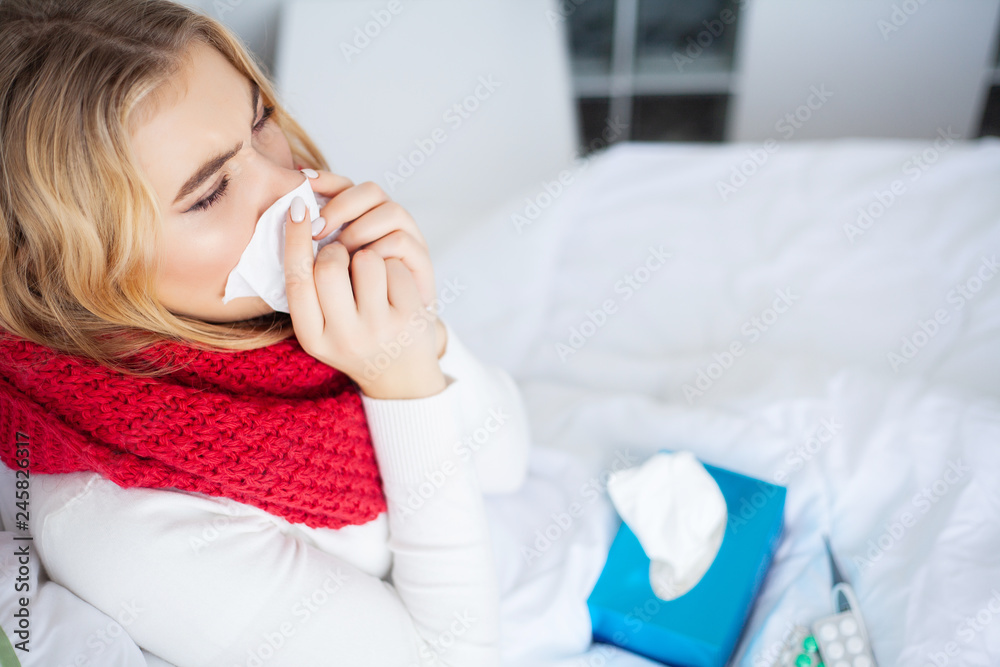 Sick Woman. Woman with flu virus lying in bed, she is measuring her temperature with a thermometer Sick Woman. Woman with flu virus lying in bed, she is measuring her temperature with a thermometer