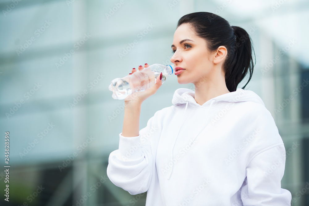 Fitness. Sport and healthy lifestyle concept - woman drinking water after exercising in park Fitness. Sport and healthy lifestyle concept - woman drinking water after exercising in park