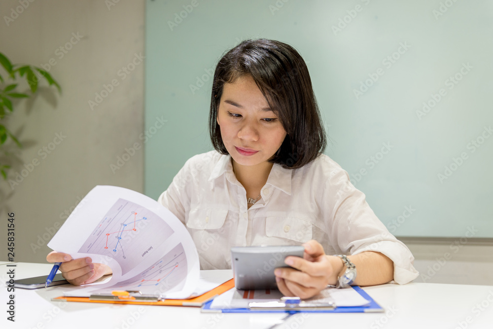 Asian businesswoman reading finance report in the office Asian businesswoman reading finance report in the office