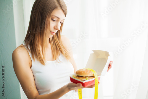 Diet. The concept of healthy and unhealthy nutrition. The model plus size makes a choice in favor of healthy food and fruit by refusing fast food and burger