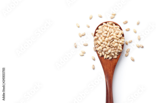 Photo Peeled barley in a wooden spoon, isolated on white background