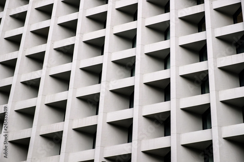 Gray concrete wall with many equal square windows. Abstract city architecture background.