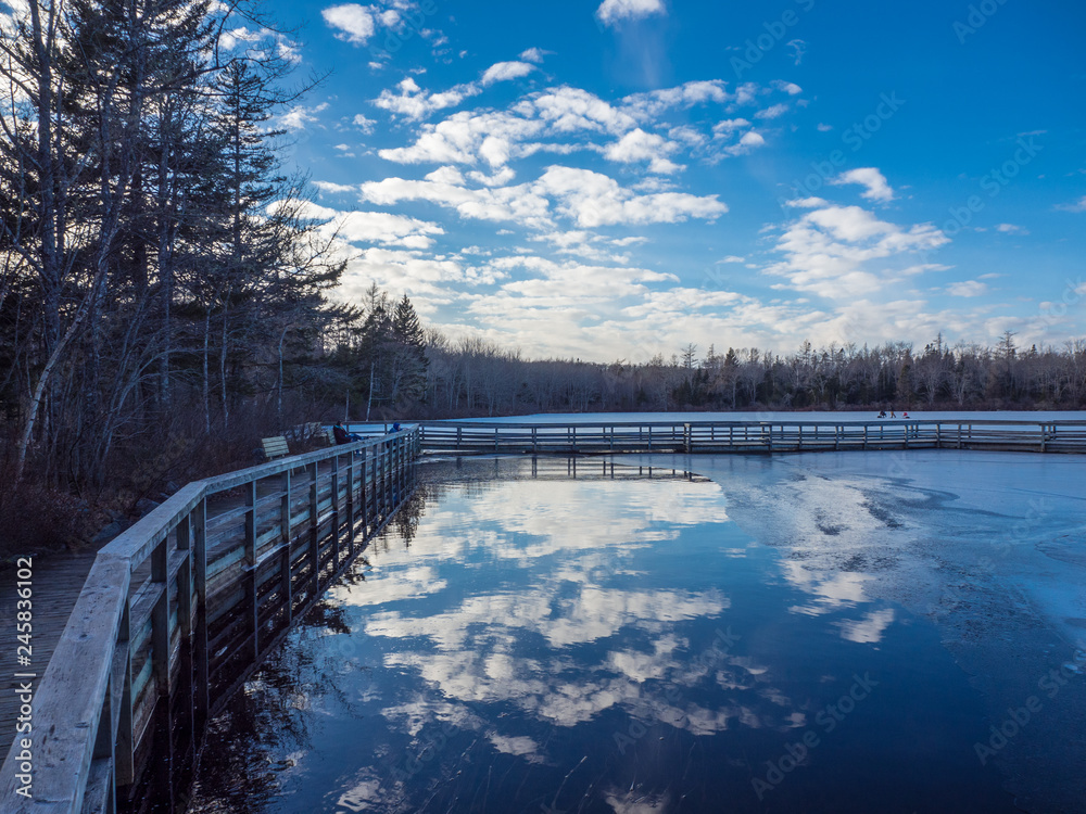 clouds reflected in lake in winter, wooden boardwalk