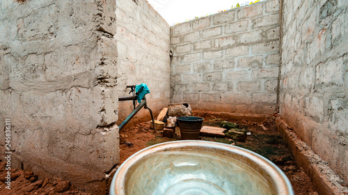 Bowl of water on dirt floor. Stone wall.