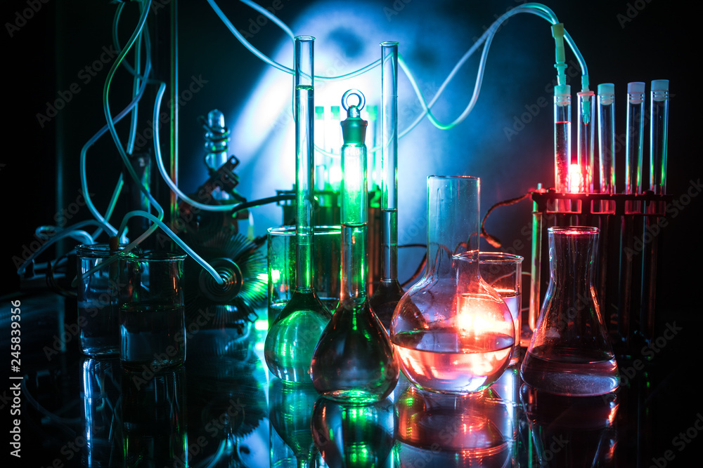 Pharmacy and chemistry theme. Test glass flask with solution in research laboratory. Science and medical background. Laboratory test tubes on dark toned background Pharmacy and chemistry theme. Test glass flask with solution in research laboratory. Science and medical background. Laboratory test tubes on dark toned background