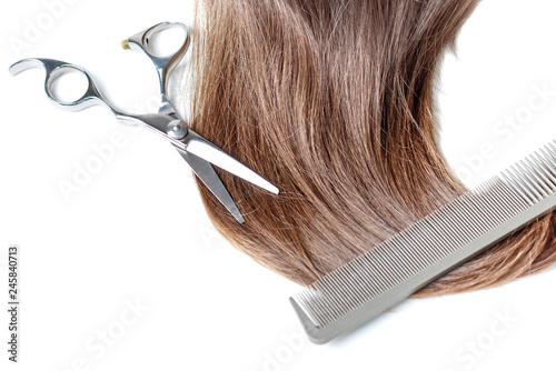 scisors, comb and brown hair isolated on white background, copy space.