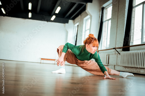 Professional yoga coach in a green turtleneck doing asana for flexibility