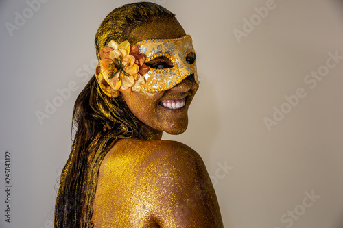 Golden Fashion art Golden skin Woman face portrait closeup. Model girl with carnival holiday golden Glamour shiny professional makeup. Gold jewellery, jewelry, mask, carnaval. Gold metallic body. © Brastock Images