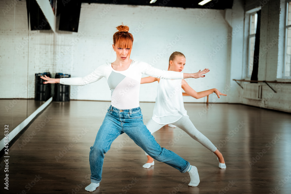 Red-haired ballet teacher and her student practicing in the dance school Red-haired ballet teacher and her student practicing in the dance school