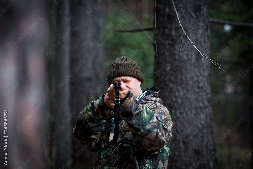 hunter with a gun in the forest cures prey