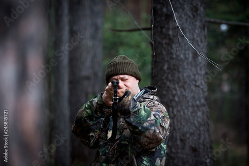 hunter with a gun in the forest cures prey