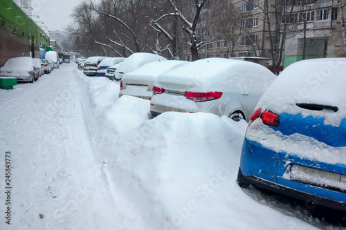 Snow covered ows of cars in the parking lot. Urban scene, snowstorm. Snowdrifts  on the road and parking lot. photo