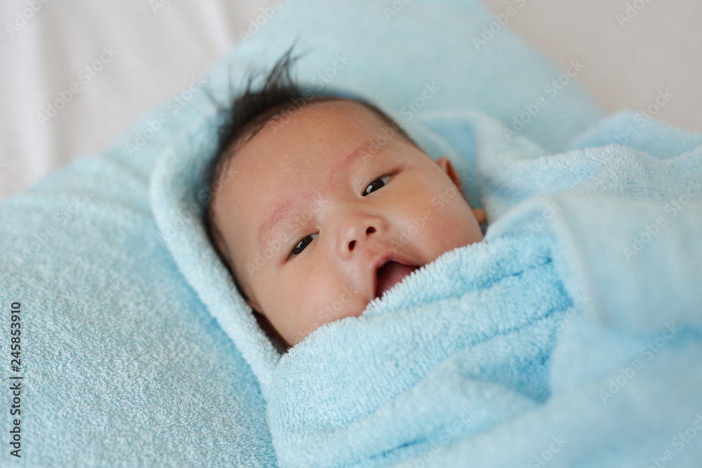 Closeup Infant baby boy in towel roll looking at camera lying on bed after bath. Closeup Infant baby boy in towel roll looking at camera lying on bed after bath.