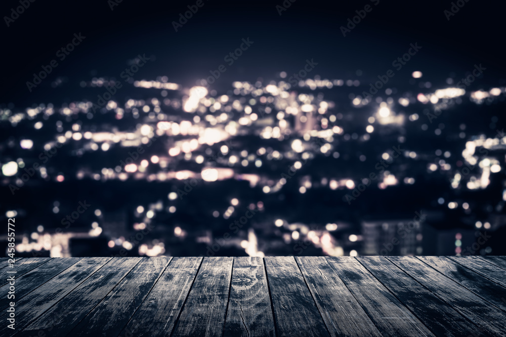 View from empty wooden plank floor above the town at night.