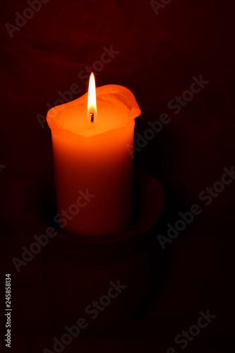 Candle flame burning in darkness on wall background. Advent or memorial prayer candle flame.