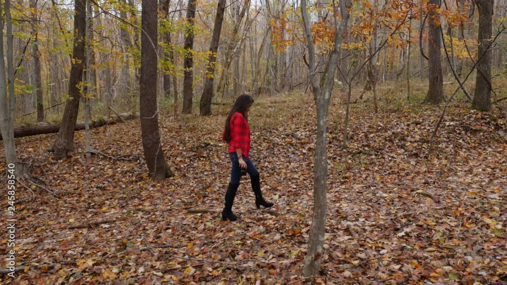 Woman holding a camera and looking for composition in autumn nature. Hiking in nature. Tracking shot Woman holding a camera and looking for composition in autumn nature. Hiking in nature. Tracking shot