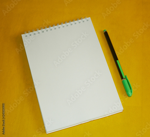 Notepad and pen on yellow background. Stationery