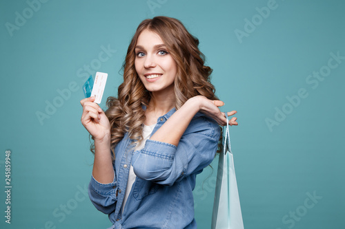Smiling handsome model posing with light blue shopping bag and two credit cards