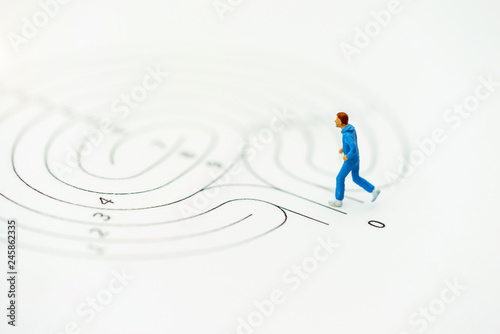 Miniature people running on start point of maze and thinking how to solve this problem. Concepts of finding a solution, problem solving and challenge.